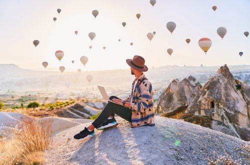 Freelancer working online at beautiful destination in Nevsehir, Goreme. Free inspired traveling blogger sitting alone on hill in scenic valley in Anatolia, Kapadokya